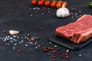 Raw fresh marbled meat and seasonings on dark background