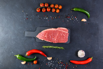 Raw fresh marbled meat and seasonings on dark background top view