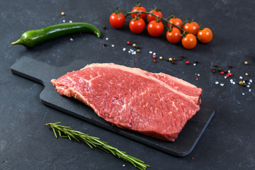 Raw fresh marbled meat and seasonings on dark background