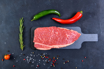 Raw fresh marbled meat and seasonings on dark background top view