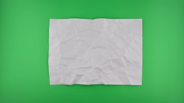 Stop motion VDO, paper ball unwrapping on green background.