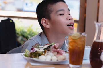 Disabled child on wheelchair with food and water on table in public restaurant, Special children's lifestyle, Life in the education age of special need child, Happy disability kid concept.