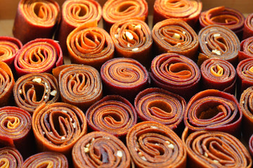 Sweet pureed fruit pastille.Fruit roll-ups homemade on a wooden background . Natural sweets from dried berries and fruits. healthy snack concept