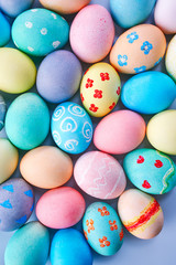 Colorful Easter eggs dyed by colored water with beautiful pattern on a pale blue background, design concept of holiday activity, top view, copy space.