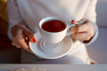Tea drinking. Woman holding a cup of hot tea in her hands. Cozy weekend.