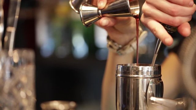 Process of pouring ingredients into shaker for making cocktail.