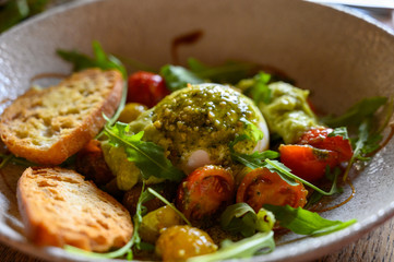 Vegetarian italian food, fresh vegetables salad with white soft burrata cheese and green pesto