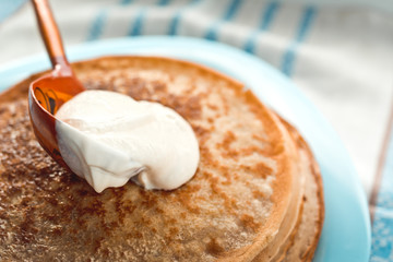 pancakes with sour cream are stacked on top of each other on a blue plate