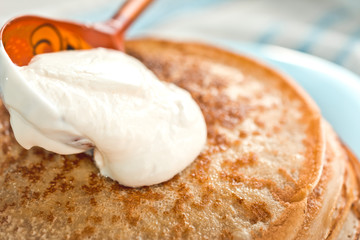 pancakes with sour cream are stacked on top of each other