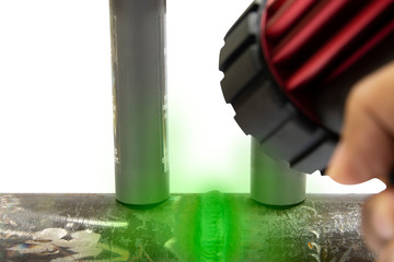 Welding on steel tubes, permanent magnets and human's hand holding the Handheld LED UV Black light Lamps. He is finding crack on the tube with Magnetic Particle Testing or MT.