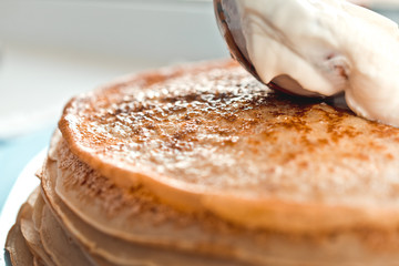 pancakes with sour cream are stacked on top of each other in close-up