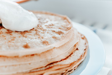 pancakes with sour cream are stacked on top of each other in close-up