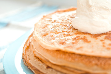 pancakes with sour cream are stacked on top of each other in close-up