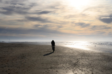 Unidentified man riding on sport bicycle on North sea sandy beach during low tide near Castricum aan Zee, Netherlands