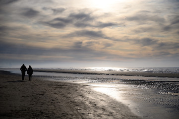 Unidentified peolpe walking on North sea sandy beach during low tide near Castricum aan Zee, Netherlands