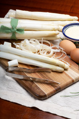 Bunch of fresh uncooked white asparagus and peeler knife, how to peel asparagus vegetables