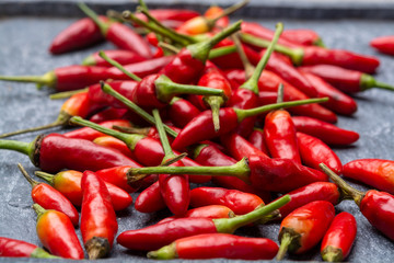 Fresh small red hot chili peppers on grey background
