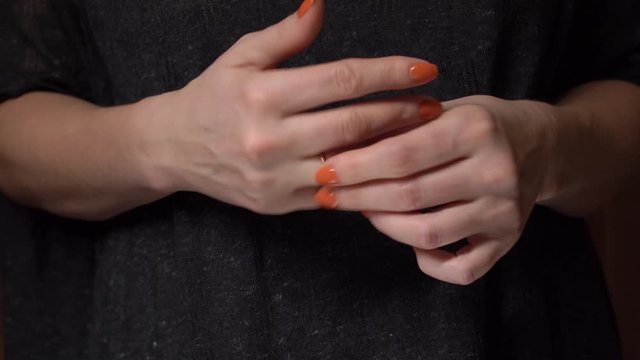 A woman is nervous, takes off and puts a wedding ring on her finger. She twists the ring nervously, wringing her fingers. We see only the hands of a woman. Excitement, experience, expectation