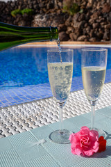 Pool party with two glasses with  bubbles white champagne or cava wine, romantic event or all inclusive holidays