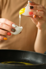Female hands break an egg, cooking egg dishes
