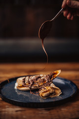 Shrove Tuesday, Pancake Day. Delicious pancakes served with fresh bananas, chocolate sauce and nuts. Concept of English traditions and food..