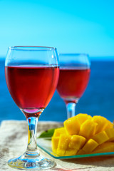 Two glasses with rose wine served outdoor with exotic fruits on tropical island La Palma, Canary islands, Spain with beautiful blue ocean view