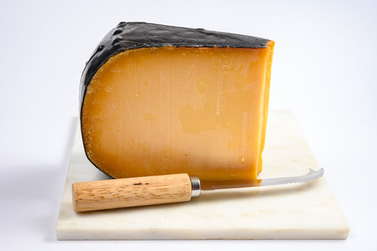One piece of old Dutch gouda cheese with black wax