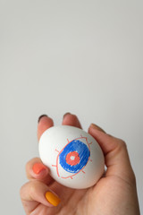 Painted egg in a female hand on a white background