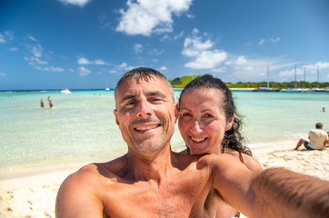 Happy familty on holiday at the beach. Young couple embracing and taking selfies on the shoreline