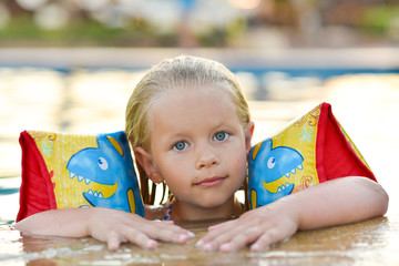 Girl in a life jacket swims in the pool