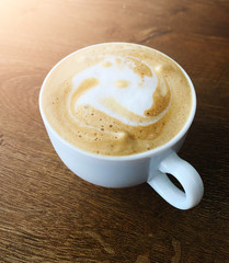 Cup of hot coffee with milk on table in cafe