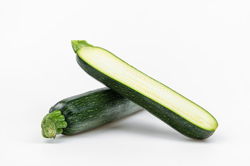 Two whole fresh zucchini and half slice isolated on white background long raw courgette