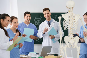 Medical students studying human skeleton anatomy in classroom