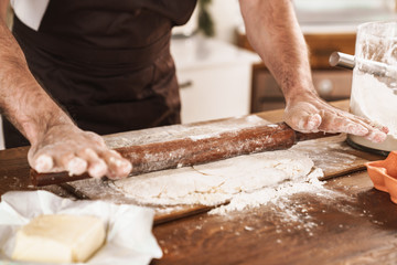 Cropped image of caucasian man in apron cooking dough
