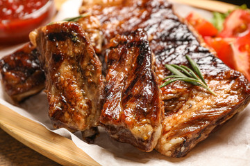 Delicious grilled ribs with rosemary on table, closeup