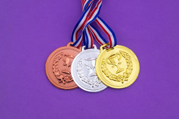 Gold, silver and bronze medal with ribbons on purple background, competition concept