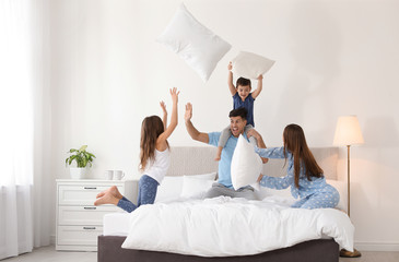 Happy family having pillow fight in bedroom - Powered by Adobe