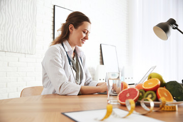 Nutritionist working with laptop at desk in office