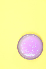 glass bowl filled with a purple liquid soap. yellow background