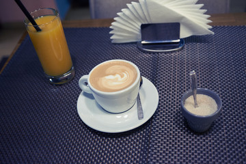 cup of coffee on the table orange juice and napkins.