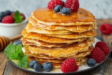 Close-up delicious pancakes, with fresh blueberries, raspberry's and honey on a light background