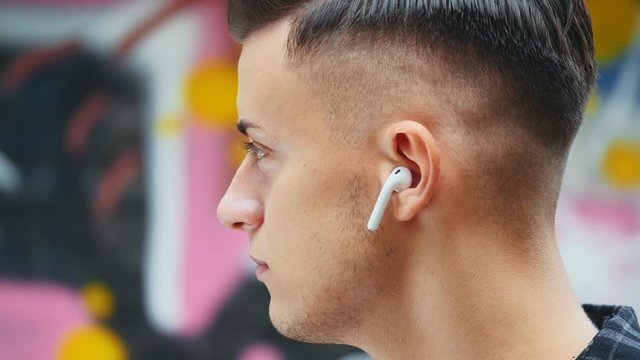 Close up. Side view. Confident and relaxed guy is listening to cool music with headphones and drinks coffee. Copy space. 4K.