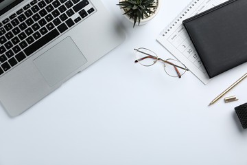 Composition with laptop, glasses and stationery on white background, top view