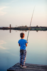 Happy child fishing on a lake in a sunny summer day.