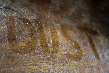 Close-up of a dusty wooden table surface with the inscription 