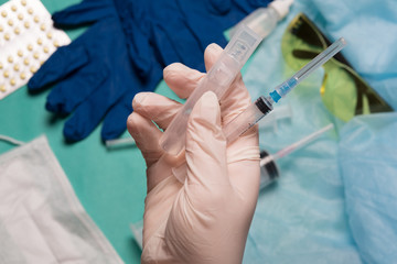 Doctor's hand holds a syringe. Hand with a syringe on a background of medical instruments.