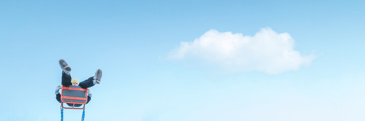 Girl swinging on swing. Kid having fun activity. Freedom lifestyle concept. Child in outdoor park. Blue sky background with cloud. Banner with copyspace. Stock photo.