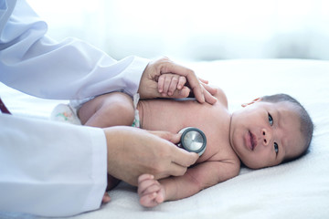Obraz na płótnie Canvas Doctor with stethoscope listening to heartbeat of newborn baby