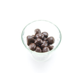 Dried fruits (raisins, dried apricots, prunes) in chocolate in a glass vase (cup) on a white isolated background.