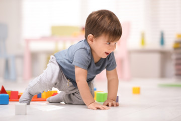 Cute little child playing with toys on floor at home